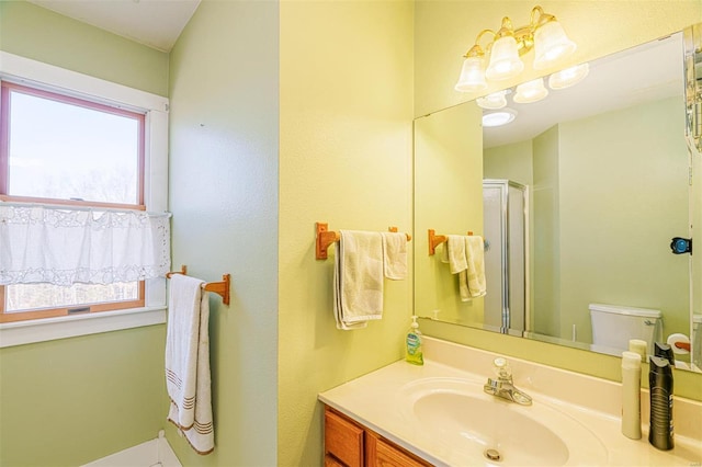 bathroom featuring toilet, a shower with door, and vanity