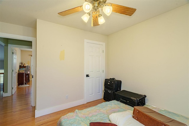 bedroom featuring ceiling fan, light wood-style flooring, and baseboards