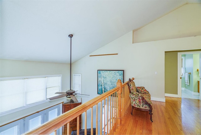 hallway with wood finished floors, high vaulted ceiling, and baseboards