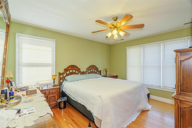 bedroom with baseboards, visible vents, ceiling fan, and light wood-style floors