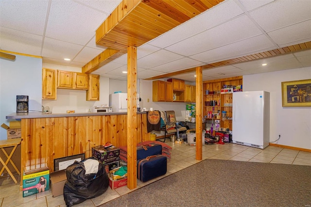 interior space with light tile patterned floors, a paneled ceiling, and freestanding refrigerator