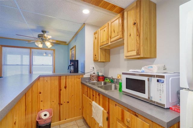 kitchen with white microwave, light tile patterned floors, a sink, a ceiling fan, and a paneled ceiling