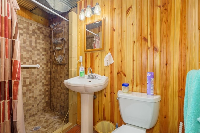 full bathroom featuring toilet, a stall shower, and wooden walls