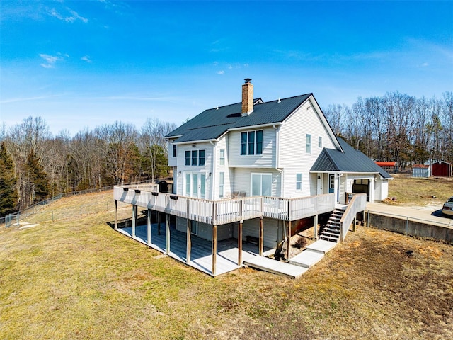 back of property featuring a wooden deck, metal roof, a lawn, stairs, and a chimney