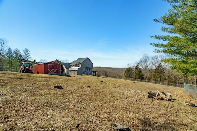 view of yard with a barn, fence, an outdoor structure, and a shed
