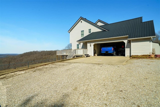 view of front of property featuring metal roof, driveway, an attached garage, and fence
