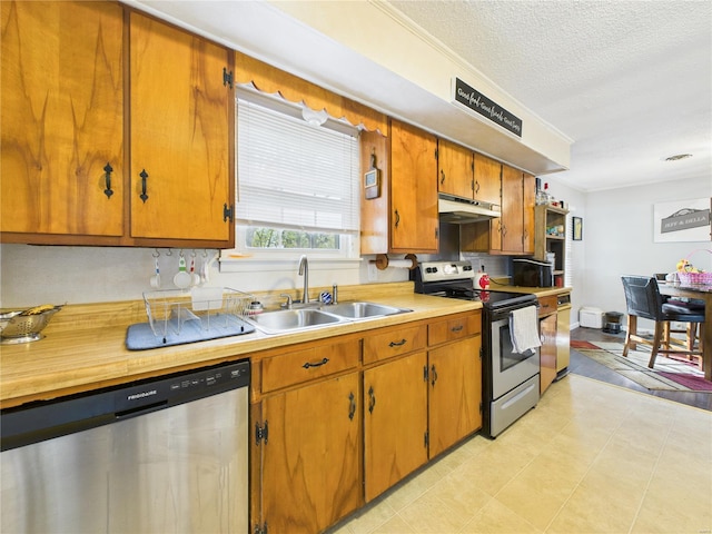 kitchen featuring stainless steel appliances, a sink, brown cabinetry, light countertops, and under cabinet range hood