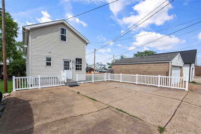 back of property featuring a detached garage, fence, and an outbuilding