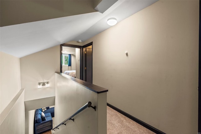 hall with baseboards, an upstairs landing, light carpet, and vaulted ceiling