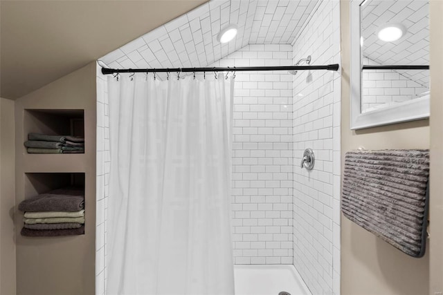 bathroom with a shower stall and lofted ceiling
