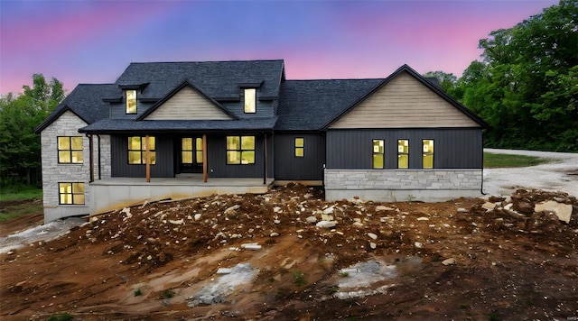 modern inspired farmhouse featuring a porch, a shingled roof, and stone siding