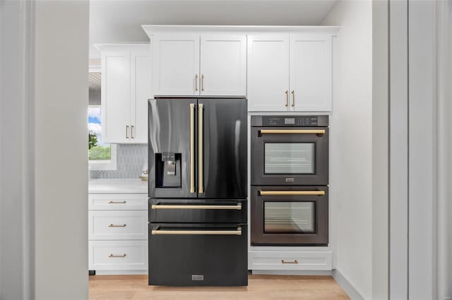 kitchen featuring stainless steel fridge, white cabinets, double oven, and light wood-type flooring