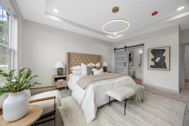 bedroom featuring recessed lighting, a barn door, baseboards, and a tray ceiling