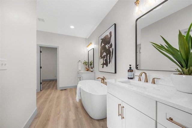 bathroom with a soaking tub, baseboards, wood finished floors, and vanity