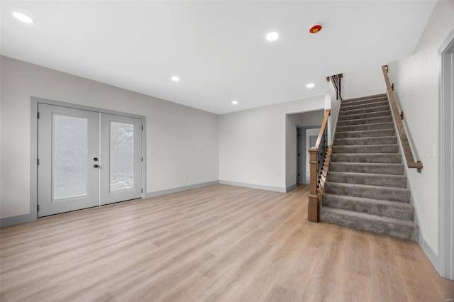 unfurnished living room with french doors, stairs, baseboards, light wood finished floors, and recessed lighting