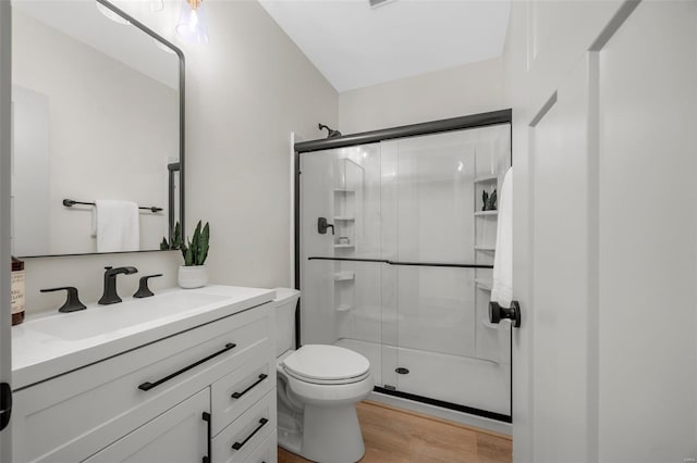 bathroom with vanity, a shower stall, toilet, and wood finished floors