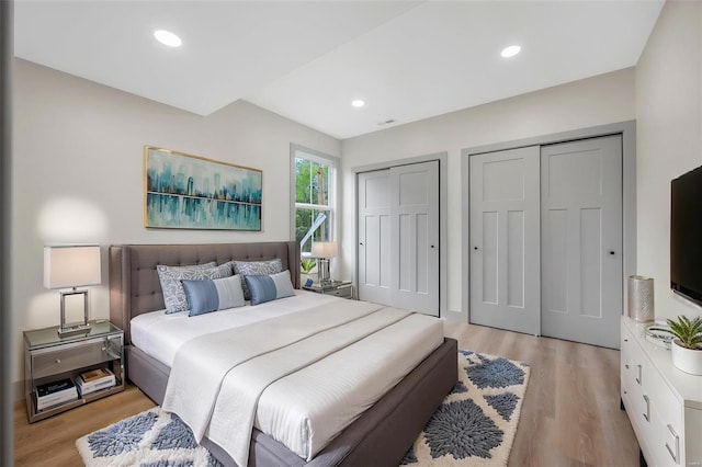 bedroom featuring recessed lighting, multiple closets, and light wood-type flooring