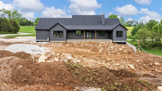 view of front of property featuring a shingled roof, covered porch, and a chimney