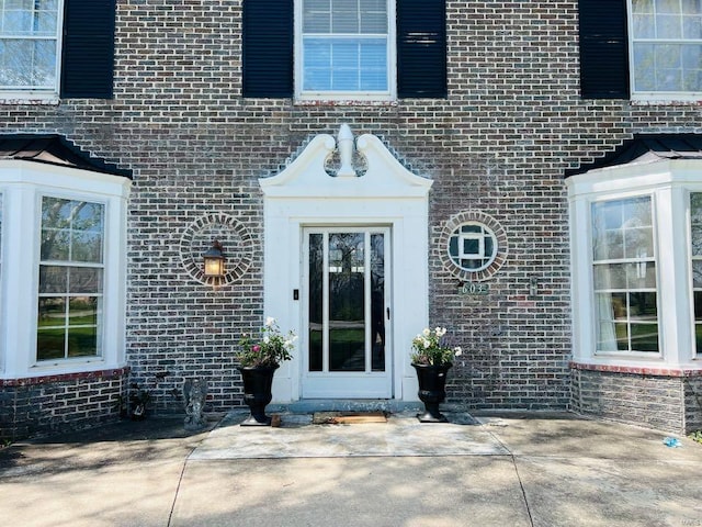 property entrance featuring brick siding and a patio