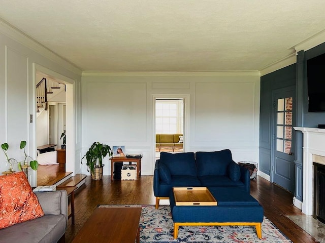 living area featuring dark wood finished floors, a decorative wall, ornamental molding, and a premium fireplace