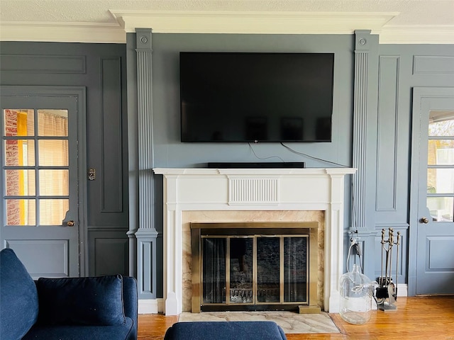 interior details with a decorative wall, ornamental molding, wood finished floors, and a fireplace