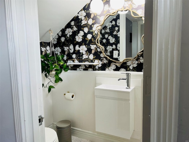 bathroom featuring toilet, vanity, wallpapered walls, and baseboards