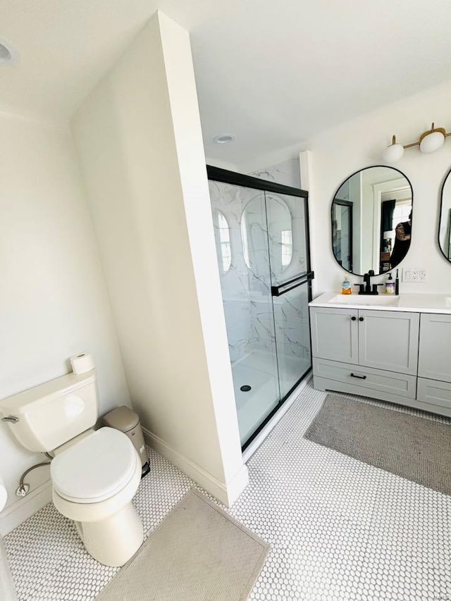 full bath featuring baseboards, a marble finish shower, vanity, and toilet