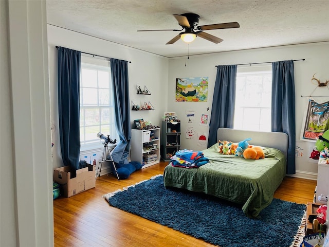 bedroom featuring wood finished floors, multiple windows, and a textured ceiling