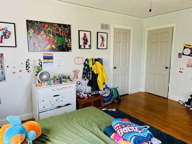 bedroom with wood finished floors, visible vents, and baseboards