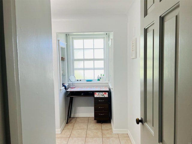 hall featuring baseboards and light tile patterned floors