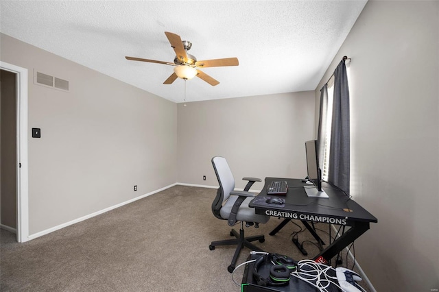 office featuring a textured ceiling, visible vents, ceiling fan, baseboards, and carpet