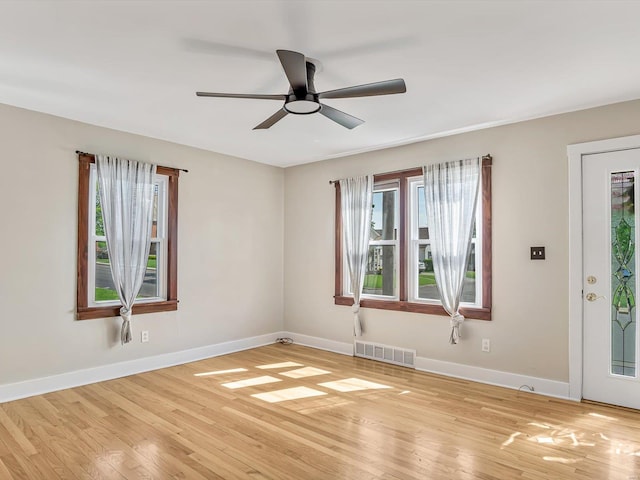 empty room with baseboards, ceiling fan, light wood-style flooring, and visible vents