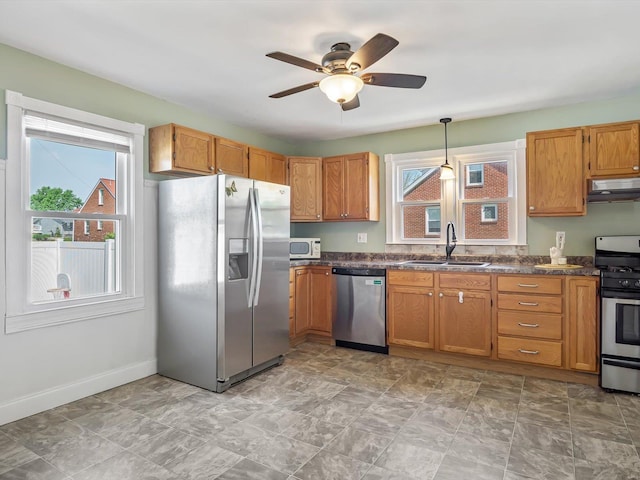 kitchen featuring a ceiling fan, appliances with stainless steel finishes, a sink, baseboards, and under cabinet range hood