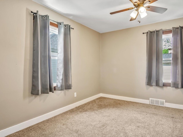 carpeted spare room featuring baseboards, ceiling fan, and visible vents