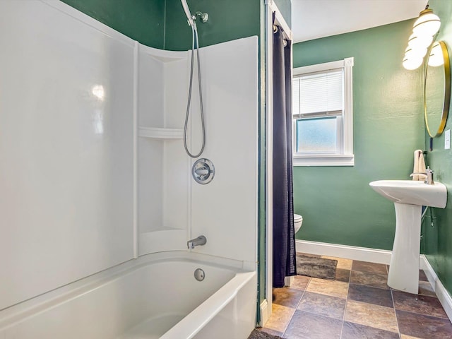 bathroom with stone finish floor, baseboards, bathtub / shower combination, and toilet