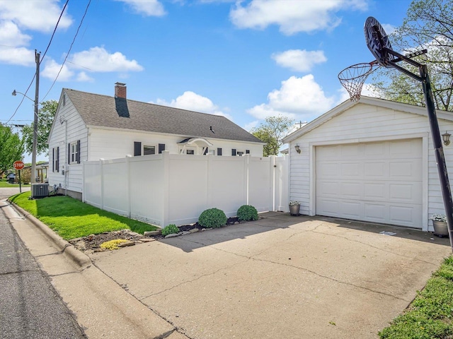 view of side of home featuring fence, concrete driveway, central AC, and a garage