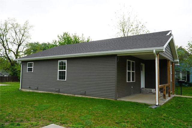 rear view of house with a lawn, a shingled roof, and a patio area