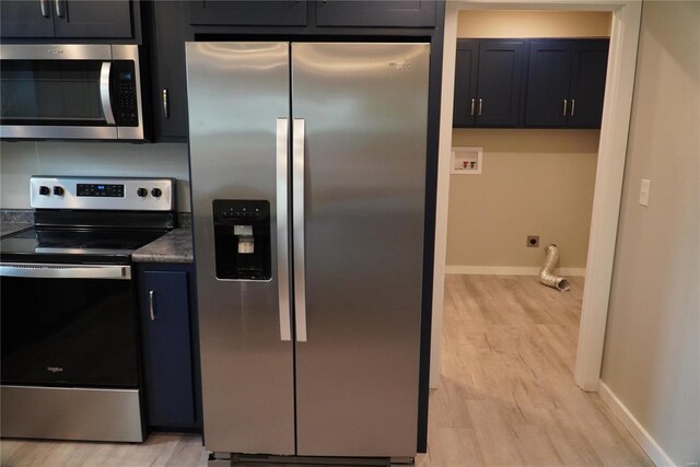 kitchen with dark countertops, baseboards, stainless steel appliances, and light wood-style flooring