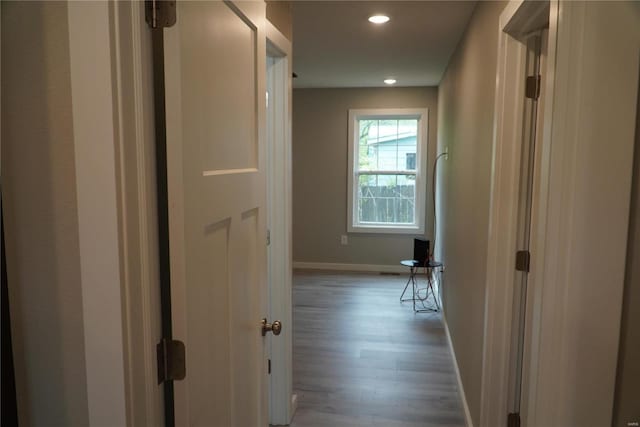 hall featuring baseboards, recessed lighting, and wood finished floors