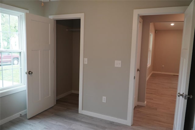 unfurnished bedroom featuring baseboards, light wood finished floors, and a closet