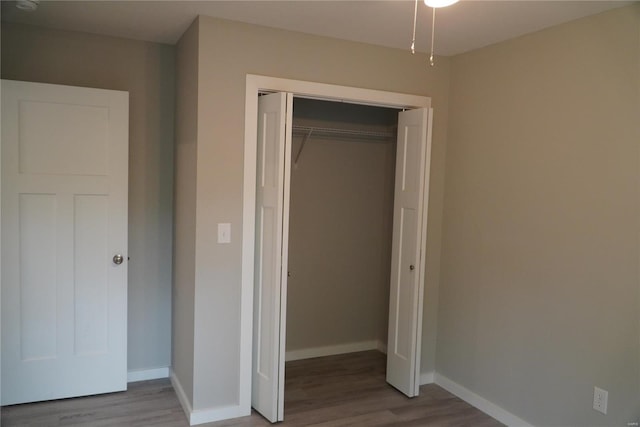 unfurnished bedroom with a closet, baseboards, and wood finished floors