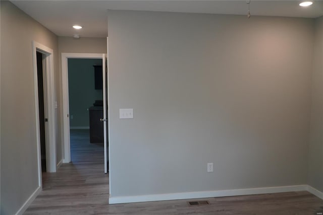 empty room featuring visible vents, recessed lighting, baseboards, and wood finished floors