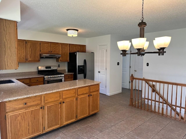 kitchen featuring a textured ceiling, a chandelier, stainless steel appliances, a peninsula, and under cabinet range hood
