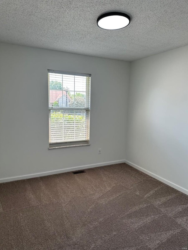 carpeted spare room featuring a textured ceiling and baseboards