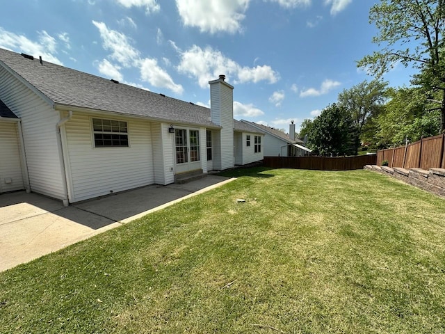 back of property with fence, a patio, roof with shingles, a chimney, and a lawn