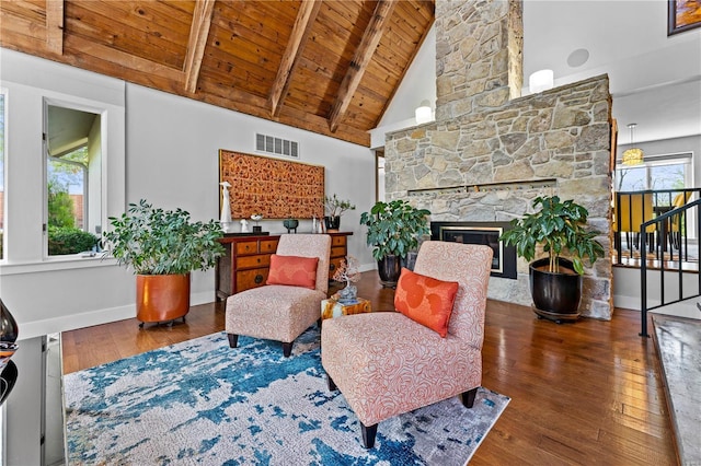 living area featuring beam ceiling, hardwood / wood-style floors, baseboards, visible vents, and wood ceiling