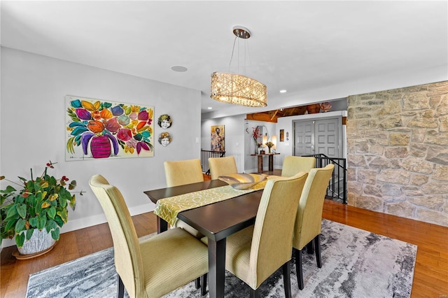 dining space featuring baseboards, an inviting chandelier, and wood finished floors
