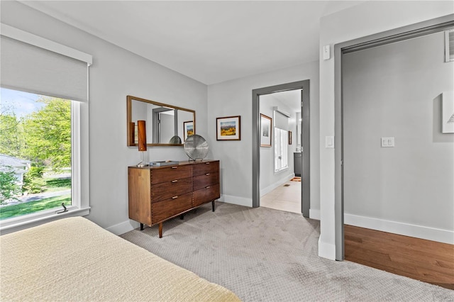 bedroom featuring baseboards, ensuite bathroom, and light colored carpet