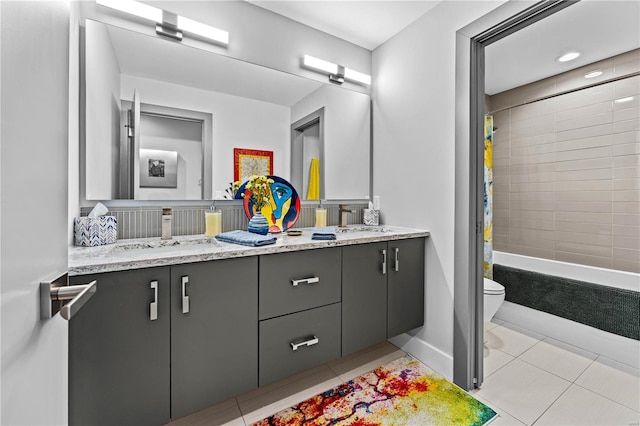 full bathroom featuring double vanity, toilet, tile patterned floors, and a sink