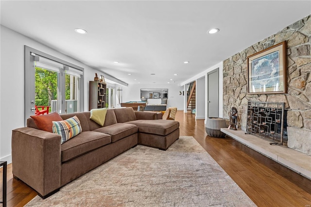 living room featuring a stone fireplace, recessed lighting, billiards, wood finished floors, and stairway